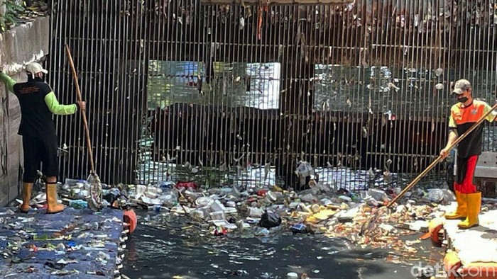Sampah tampak menumpuk di Pintu Air Grogol, Jakarta Barat, Jumat (10/09/2021). Petugas pun sibuk membersihkan dengan alat seadanya.