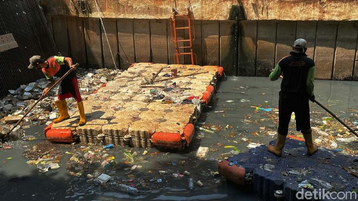 Sampah tampak menumpuk di Pintu Air Grogol, Jakarta Barat, Jumat (10/09/2021). Petugas pun sibuk membersihkan dengan alat seadanya.