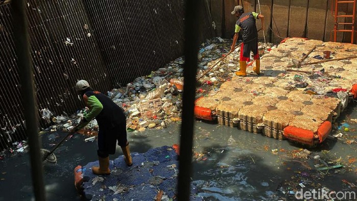 Sampah tampak menumpuk di Pintu Air Grogol, Jakarta Barat, Jumat (10/09/2021). Petugas pun sibuk membersihkan dengan alat seadanya.