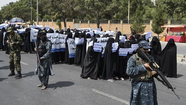 Armed Taliban fighters escort veiled women as they march during a pro-Taliban rally outside Shaheed Rabbani Education University in Kabul on September 11, 2021. (Photo by Aamir QURESHI / AFP)