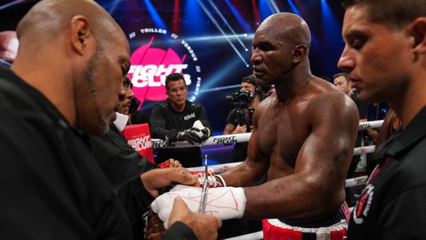 Former heavyweight champion Evander Holyfield, center, has his gloves and hand wraps removed after losing in the first round of a boxing match against former MMA star Vitor Belfort, Saturday, Sept. 11, 2021, in Hollywood, Fla. (AP Photo/Rebecca Blackwell)