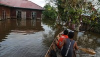Warga menggunakan perahu untuk melintasi banjir yang merendam permukiman sekitar rumahnya di Jalan Kelud, Kasongan, Kabupaten Katingan, Kalimantan Tengah.