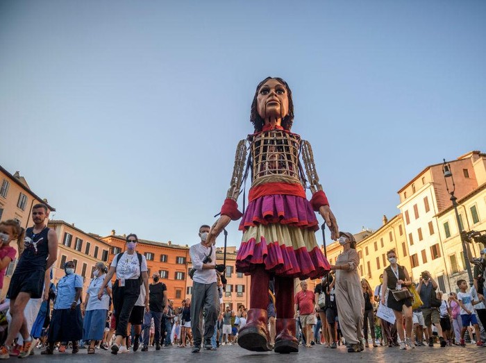 ROME, ITALY - SEPTEMBER 12: People greet Little Amal, a giant puppet depicting a young Syrian refugee girl, as she walks in the city, on September 12, 2021 in Rome, Italy. Little Amal is a 3.5 meter puppet walking 8,000 kilometers across Europe to highlight the plight of child refugees. There are some 26 million refugees worldwide, and more than half of them are children. (Photo by Antonio Masiello/Getty Images)