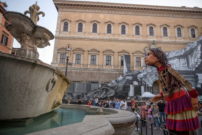 ROME, ITALY - SEPTEMBER 12: People greet Little Amal, a giant puppet depicting a young Syrian refugee girl, as she walks in the city, on September 12, 2021 in Rome, Italy. Little Amal is a 3.5 meter puppet walking 8,000 kilometers across Europe to highlight the plight of child refugees. There are some 26 million refugees worldwide, and more than half of them are children. (Photo by Antonio Masiello/Getty Images)