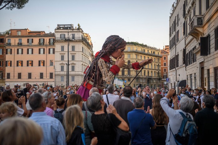 Boneka Raksasa Little Amal saat Keliling Italia ROME, ITALY - SEPTEMBER 12: People greet Little Amal, a giant puppet depicting a young Syrian refugee girl, as she walks in the city, on September 12, 2021 in Rome, Italy. Little Amal is a 3.5 meter puppet walking 8,000 kilometers across Europe to highlight the plight of child refugees. There are some 26 million refugees worldwide, and more than half of them are children. (Photo by Antonio Masiello/Getty Images)