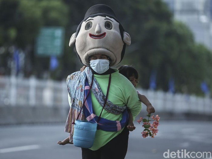 Dibalut kostum karakter, Asih (33) bersama buah hatinya Delisah (3) berjalan kaki mengharap belas kasih dari pengguna jalan di Ibu Kota.