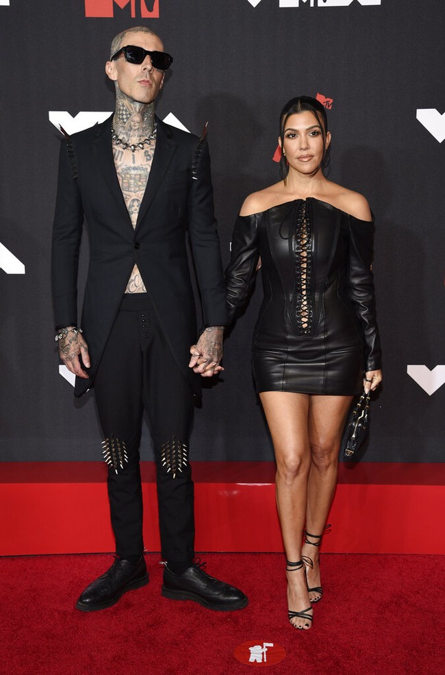 Kourtney Kardashian dan Travis Barker tampil kompak dengan busana bernuansa hitam. Kourtney mengenakan mini dress kulit dari desainer Olivier Theyskens. Dress bustier itu memiliki detail tali pada bagian depan sehingga membuat bagian tubuh Kourtney dari dada hingga perut tampak mengintip dari balik busananya. Foto: Evan Agostini/ Invision/AP/Evan Agostini