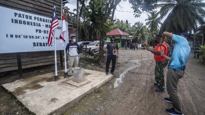 RUMAH TERLETAK DI DUA NEGARA Wisatawan berada di halaman rumah perbatasan patok 3 Indonesia-Malaysia di Pulau Sebatik, Nunukan, Kalimantan Utara, Senin (13/9/2021). Rumah tersebut terletak di dua negara, dimana ruang tamu di Indonesia sementara ruang baca dan dapur di Malaysia. ANTARA FOTO/Muhammad Adimaja/hp.