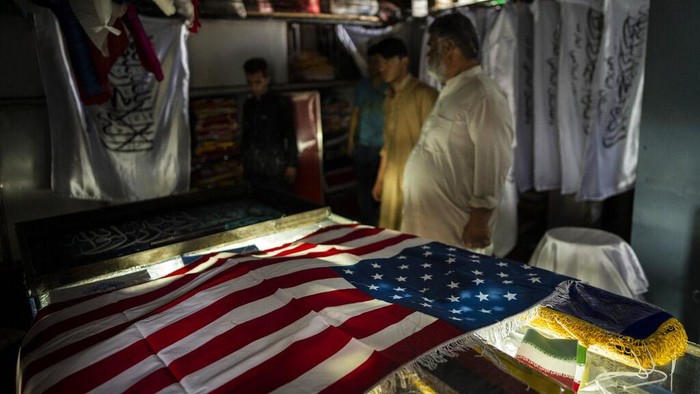 Taliban Berkuasa, Tukang Sablon Banjir Order American and Taliban flags are seen in flag printing workshop in Kabul's Jawid market, Afghanistan, Sunday, Sept. 12, 2021. The small flag shop, tucked away in the courtyard of a Kabul market, has documented Afghanistan’s turbulent history over the decades with its ever-changing merchandise. Now the shop is filled with white Taliban flags, emblazoned with the Quran's Muslim statement of faith, in black Arabic lettering. (AP Photo/Bernat Armangue)