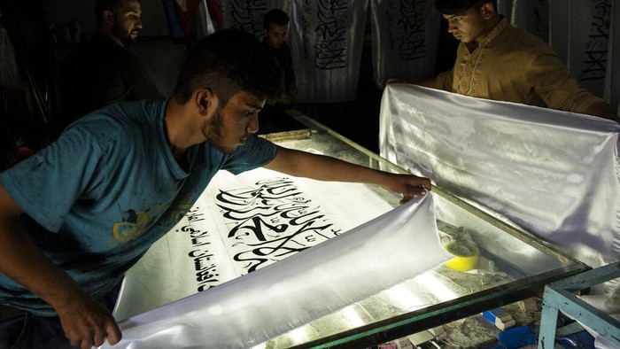 Taliban Berkuasa, Tukang Sablon Banjir Order American and Taliban flags are seen in flag printing workshop in Kabul's Jawid market, Afghanistan, Sunday, Sept. 12, 2021. The small flag shop, tucked away in the courtyard of a Kabul market, has documented Afghanistan’s turbulent history over the decades with its ever-changing merchandise. Now the shop is filled with white Taliban flags, emblazoned with the Quran's Muslim statement of faith, in black Arabic lettering. (AP Photo/Bernat Armangue)