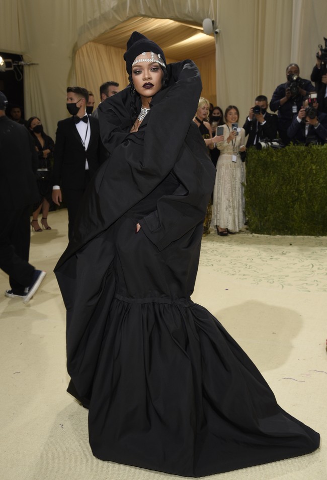 Bukan Rihanna namanya jika gayanya tak menghebohkan. Pilihannya kali ini jatuh pada gaun hitam bergaya piama oversized dengan kerah dramatis dari rumah mode Balenciaga. Aku seorang imigran. Itu caraku memaknai temanya, ujar pelantun Umbrella itu tentang inspirasi di balik gaun tersebut. (Foto: Invision/Evan Agostini/AP)