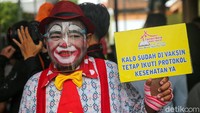 Meski cuaca hujan, para badut ini tetap semangat untuk mengajak masyarakat mendapatkan vaksin COVID-19.