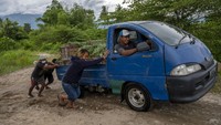 Sejumlah warga dan pengendara sepeda motor atau mobil saling bantu membantu agar bisa melintas di jembatan darurat yang dibuat secara swadaya di Desa Jono Oge, Sigi, Sulawesi Tengah, Senin (13/9/2021). Jalur ini terbilang cukup ekstrem dengan medan yang curam.