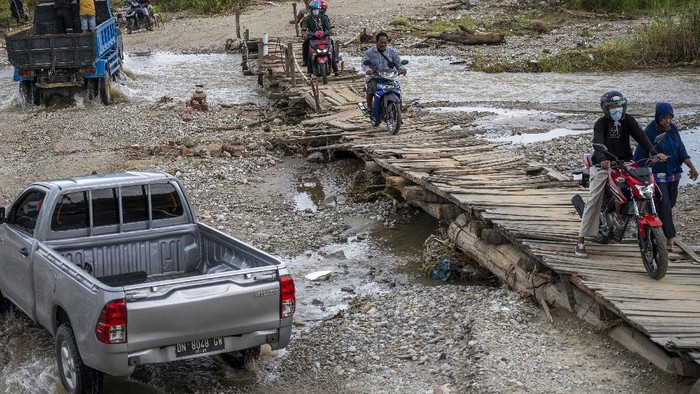 Sejumlah warga membantu mendorong sebuah mobil yang tidak bisa melewati jembatan darurat di Desa Jono Oge, Sigi Sulawesi Tengah, Senin (13/9/2021). Jalan yang menghubungkan sejumlah kecamatan di Kabupaten Sigi itu terendam air sungai yang meluap sejak sepekan lalu dan hingga kini belum mendapat penanganan dari instansi terkait sehingga masyarakat setempat berinisiatif membuat jembatan darurat secara swadaya agar dapat dilintasi. ANTARA FOTO/Basri Marzuki/hp.