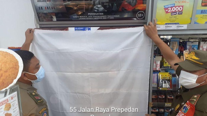 Satpol PP Jakarta Barat tutupi produk rokok di minimarket.