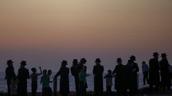 Menengok Ritual Pembersihan Dosa di Tahun Baru Yahudi Ultra-Orthodox Jews of the Kiryat Sanz Hassidic sect listen to their rabbi on a hill overlooking the Mediterranean Sea as they participate in a Tashlich ceremony, in Netanya, Israel, Tuesday, Sept. 14, 2021. Tashlich, which means