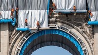 Para pekerja memulai proses membungkus monumen Arc De Triomphe dengan kain perak di Paris, Prancis.  