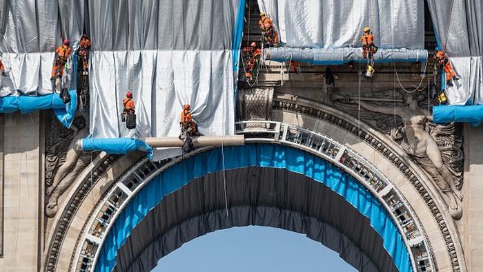 PARIS, FRANCE - SEPTEMBER 12: Workers begin the process of wrapping up the Arc De Triomphe monument in silver-blue fabric on September 12, 2021, in Paris, France. The monumental installation will wrap the landmark Parisian monument under a 25,000 square meters silver and blue fabric. 