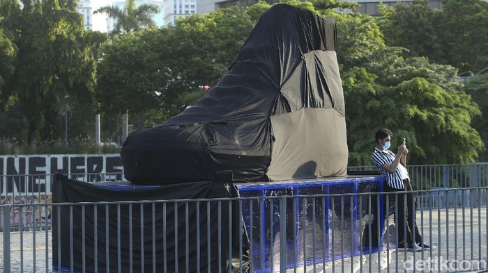 Pak Anies, Ada Tugu Sepatu Baru di Sudirman? Sebuah kain hitam menutupi benda berbentuk sepatu besar di Kawasan Sudirman, Jakarta, Rabu (15/9/2021). Penasaran?