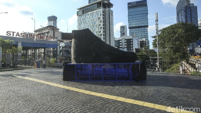 Sebuah kain hitam menutupi benda berbentuk sepatu besar di Kawasan Sudirman, Jakarta, Rabu (15/9/2021). Penasaran?