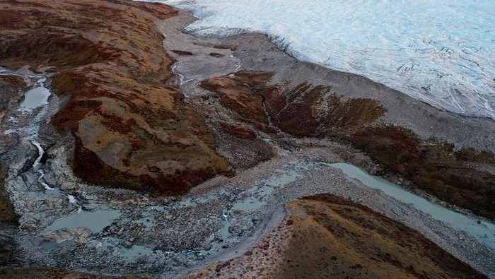 KANGERLUSSUAQ, GREENLAND - SEPTEMBER 09:  A tourist photographs near meltwater running past the retreating Russell Glacier on September 09, 2021 near Kangerlussuaq, Greenland. 2021 will mark one of the biggest ice melt years for Greenland in recorded history. Researchers from Denmark estimated that in July of this year enough ice melted on the Greenland Ice Sheet to cover the entire state of Florida with two inches of water. According to NASA, 5 trillion tons of ice have melted in Greenland over approximately the past 15 years, enough to increase global sea level by nearly an inch. The observations come on the heels of the recent United Nations report on global warming which stated that accelerating climate change is driving an increase in extreme weather events. (Photo by Mario Tama/Getty Images)