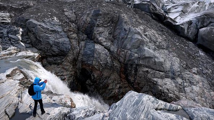 Pemanasan Global Jadi Ancaman Mengerikan Selain Corona KANGERLUSSUAQ, GREENLAND - SEPTEMBER 09: A tourist photographs near meltwater running past the retreating Russell Glacier on September 09, 2021 near Kangerlussuaq, Greenland. 2021 will mark one of the biggest ice melt years for Greenland in recorded history. Researchers from Denmark estimated that in July of this year enough ice melted on the Greenland Ice Sheet to cover the entire state of Florida with two inches of water. According to NASA, 5 trillion tons of ice have melted in Greenland over approximately the past 15 years, enough to increase global sea level by nearly an inch. The observations come on the heels of the recent United Nations report on global warming which stated that accelerating climate change is driving an increase in extreme weather events. (Photo by Mario Tama/Getty Images)
