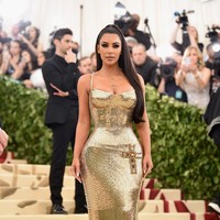 Kim Kardashian menebar pesonanya dalam balutan gaun emas mengilap Versace di MET Gala 2018 yang mengusung tema Heavenly Bodies: Fashion & The Catholic Imagination. Menyesuaikan tema, gaun tersebut dihiasi salib pada bagian rok. (Foto: Getty Images/Jason Kempin)