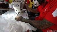 Tampak seorang napi bertato sedang menjahit pakaian.