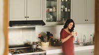 Tampak anggun dengan gaun merahnya, Raisa sangat menikmati kopinya di pagi hari. Ia berpose di dapur favoritnya. Foto: Instagram @raisa6690