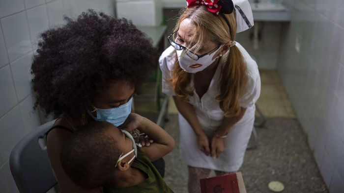 A nurse greets a young girl as she arrives with her mother to receive a dose of the Soberana-02 COVID-19 vaccine, in Havana, Cuba, Thursday, Sept. 16, 2021. Cuba began inoculating children as young as 2-years-old with locally developed vaccines on Thursday.(AP Photo/Ramon Espinosa)