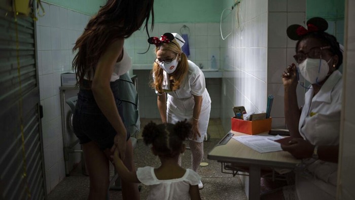 A nurse greets a young girl as she arrives with her mother to receive a dose of the Soberana-02 COVID-19 vaccine, in Havana, Cuba, Thursday, Sept. 16, 2021. Cuba began inoculating children as young as 2-years-old with locally developed vaccines on Thursday.(AP Photo/Ramon Espinosa)