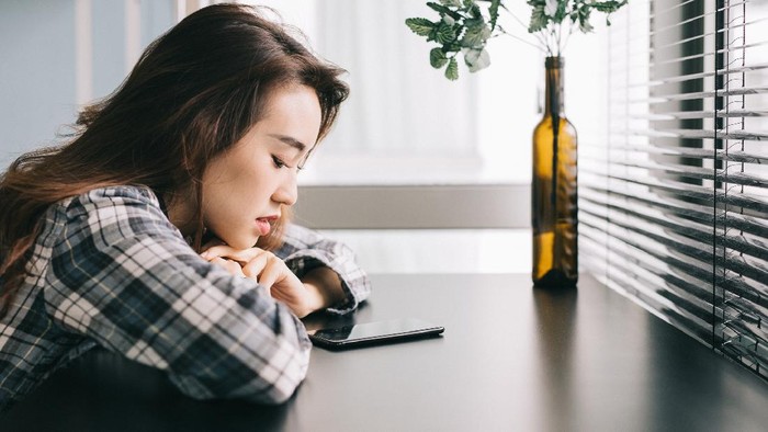 Foto ilustrasi wanita yang mengalami ghosting. Young woman with smartphone waiting for a text from her friend