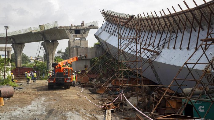 Workers stand near an under-construction bridge that collapsed in Mumbai, India, Friday, Sept. 17, 2021. According to police more than a dozen people were injured after a part of the under-construction bridge collapsed early Friday morning in Mumbai. (AP Photo/Rafiq Maqbool)