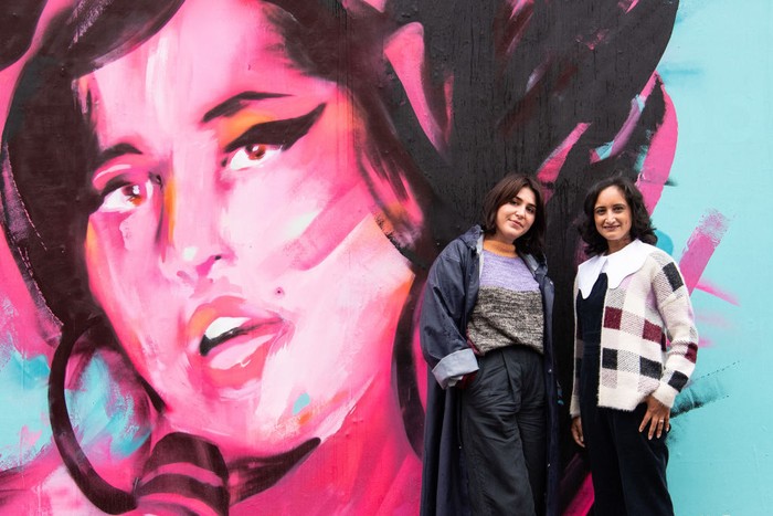 Mural Amy Winehouse di Inggris LONDON, ENGLAND - SEPTEMBER 14: (L-R) Exhibition curator Priya Khanchandani and Naomi Parry attend a mural unveiling to mark the Design Museum's Amy Winehouse exhibition announcement in Camden on September 14, 2021 in London, England. (Photo by Jeff Spicer/Getty Images)