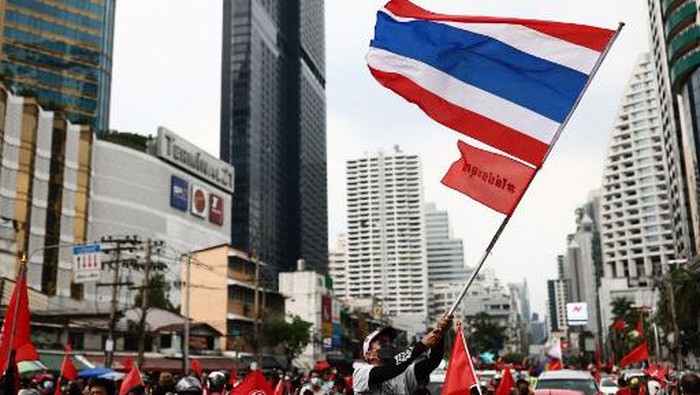 An anti-government protester waves a national flag as they gather for a demonstration to mark the 15-year anniversary of the 2006 military takeover in Bangkok on September 19, 2021, and urge the resignation of the current administration over its handling of the Covid-19 coronavirus crisis. (Photo by Jack TAYLOR / AFP)