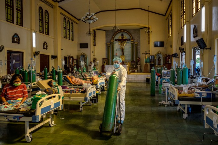 MANILA, PHILIPPINES - AUGUST 25: A healthcare worker moves an oxygen tank as patients infected with Covid-19 are treated at a chapel converted into a Covid-19 intensive care unit on August 25, 2021 in Quezon city, Metro Manila, Philippines. Hospitals in the Philippines are running out of beds for Covid-19 patients as the country struggles to cope with a huge wave of cases fueled by the more infectious Delta variant. Recording more than 1.8 million cases and more than 32,000 deaths, the Philippines continues to suffer the second-worst outbreak of the pandemic in Southeast Asia, with every one out of four people tested turning out positive for the coronavirus. (Photo by Ezra Acayan/Getty Images)