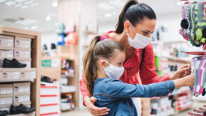 Mother and small daughter with face mask shopping in shoeshop coronavirus concept.