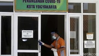 Petugas kebersihan tengah membersihkan pintu masuk gedung.
