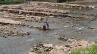 Melongok ke arah sungai, tampak orang-orang yang didominasi keluarga tengah berada di pinggir sungai. Sementara, tampak beberapa mobil terparkir di pinggir jalan tersebut. (Pradito Rida Pertana/detikTravel)