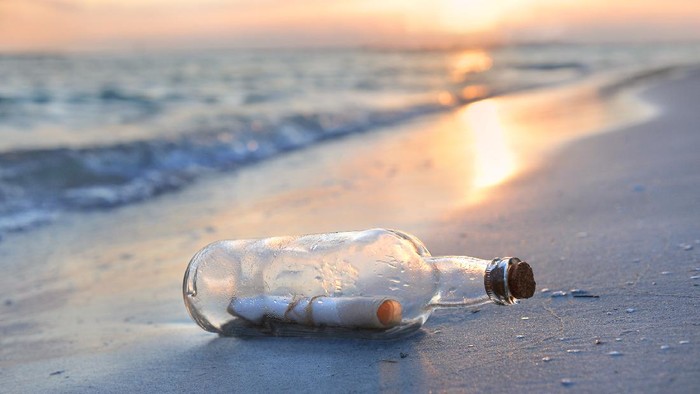 Message in a bottle resting on shore during sunset