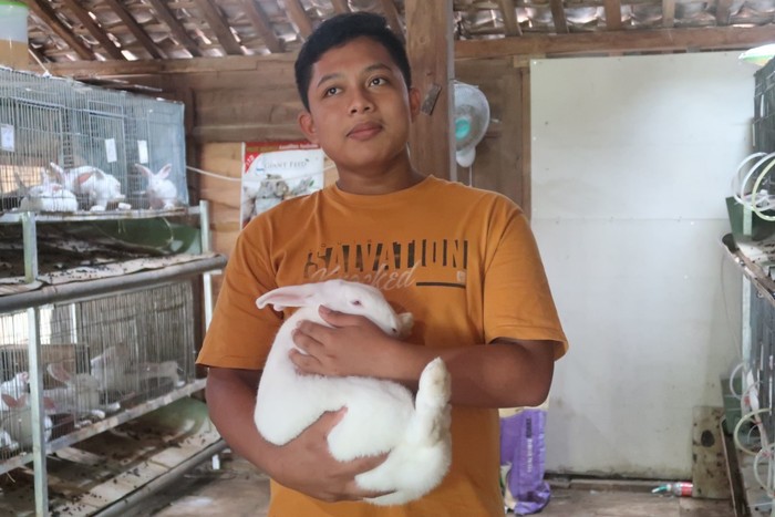 Genthur Rahmadhani (15)  menggendong kelinci yang diternakkannya