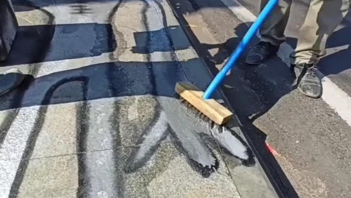 Petugas membersihkan gambar alien di pedestrian Dago