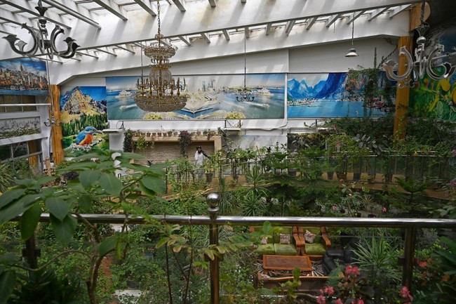 Di dalam rumah, terdapat semacam taman besar yang penuh tumbuhan tropis dengan langit-langit kaca yang dihiasi berbagai lampu kristal gantung. Bagian tengahnya diisi sofa dan meja untuk bersantai. Berbagai lukisan berukuran besar yang didominasi gambar pemandangan dan kuda-kuda yang menghiasi hampir di setiap sudut rumah semakin mempertegas kemewahan rumah tersebut. (Foto: AFP/WAKIL KOHSAR)