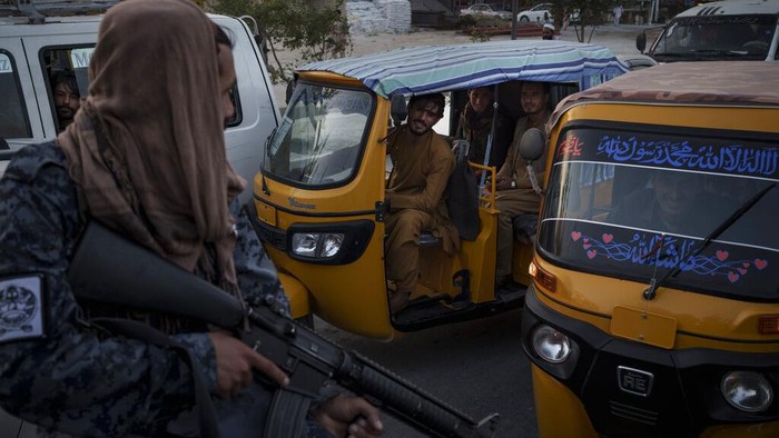 Afghan drivers and passengers stuck in a traffic jam look at Taliban fighters riding in the back of a pickup truck in Kabul, Afghanistan, Monday, Sept. 20, 2021. (AP Photo/Felipe Dana)