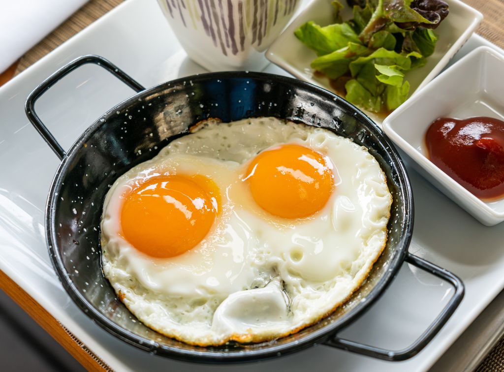 Breakfast - Sunny side up fried eggs with tomato sauce and potato wedges