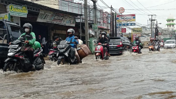 Jalan Raya Sawangan tergenang air setinggi 30 Cm, lalu lintas macet. Pengendara motor ada yang mogok.