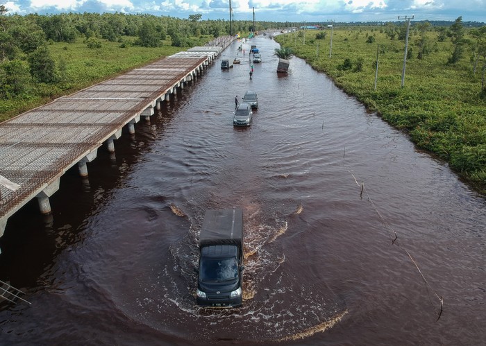 Foto udara pengendara mobil berusaha menerobos banjir yang merendam di jalan trans Kalimantan Bukit Rawi, Pulang Pisau, Kalimantan Tengah, Kamis (23/9/2021). Banjir luapan Sungai Kahayan dan Sungai Rungan kiriman dari wilayah hulu tersebut masih merendam sepanjang 2,5 kilometer jalan nasional Kalimantan Bukit Rawi sejak Senin (30/8/2021) dan akibatnya akses jalan tidak bisa dilalui kendaraan bermotor. ANTARA FOTO/Makna Zaezar/foc.