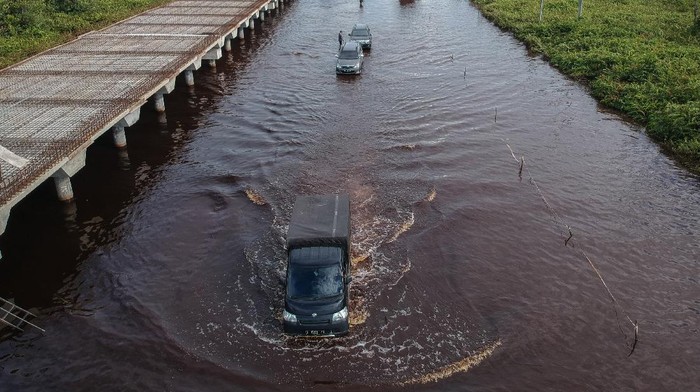 JALAN TRANS KALIMANTAN BUKIT RAWI MASIH TERENDAM BANJIR Foto udara pengendara mobil berusaha menerobos banjir yang merendam di jalan trans Kalimantan Bukit Rawi, Pulang Pisau, Kalimantan Tengah, Kamis (23/9/2021). Banjir luapan Sungai Kahayan dan Sungai Rungan kiriman dari wilayah hulu tersebut masih merendam sepanjang 2,5 kilometer jalan nasional Kalimantan Bukit Rawi sejak Senin (30/8/2021) dan akibatnya akses jalan tidak bisa dilalui kendaraan bermotor. ANTARA FOTO/Makna Zaezar/foc.