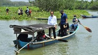 Jokowi yang memakai baju putih tampak berdiri bersama Anan Nurakhman. Sementara itu, para nelayan tampak mengayuh menuju seberang sungai. (Foto: Agus Suparto)