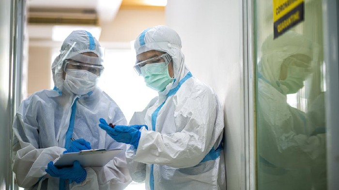 Asian doctor holding checking coronavirus or covid-19 infected patient name list sheet in quarantine area in hospital